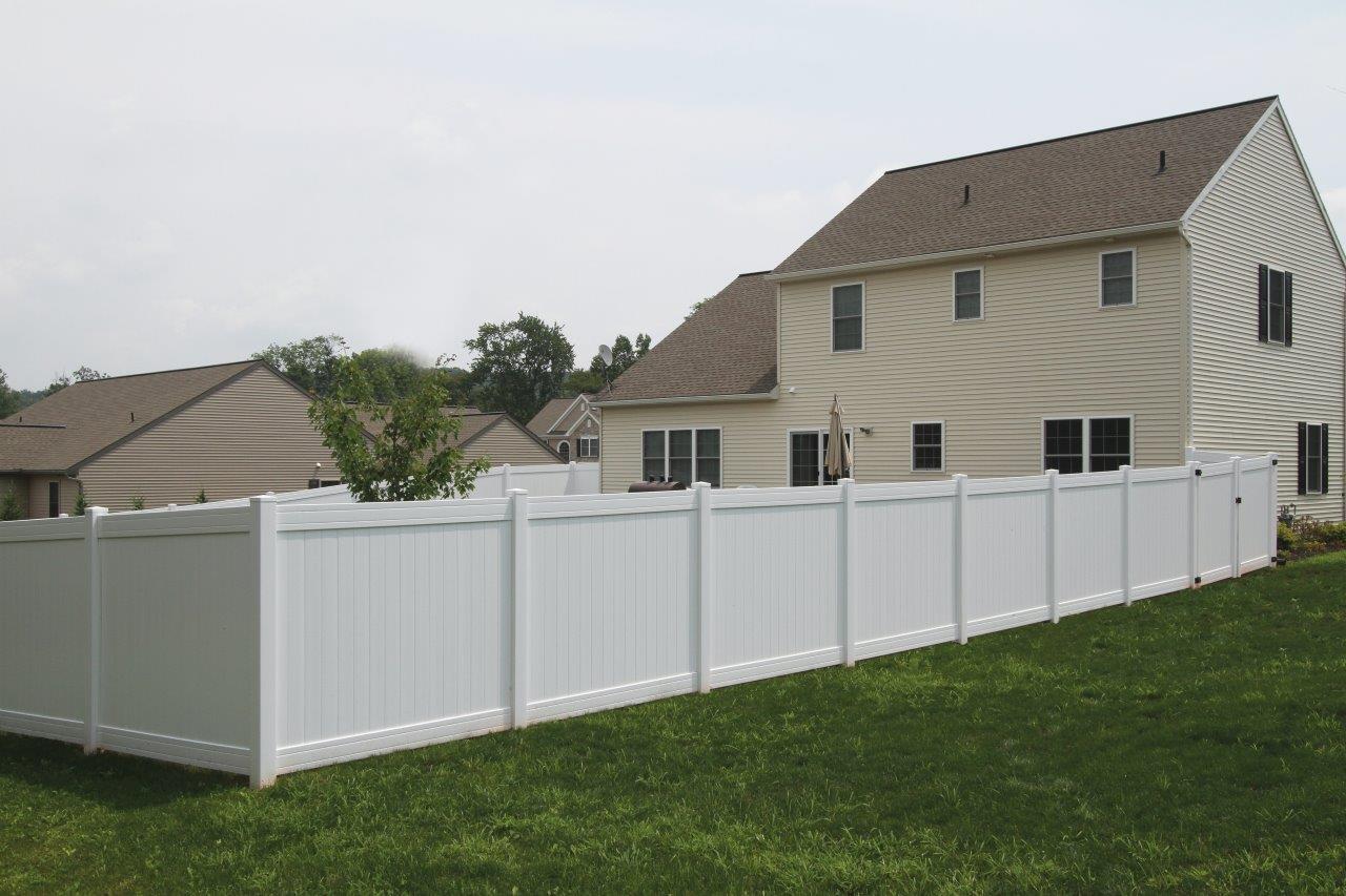 External view of white privacy fence in surrounding the backyard of a suburban home